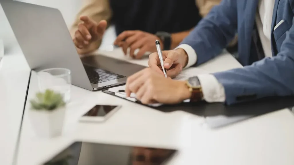Desk with professional businessmen working with a laptop and notepad